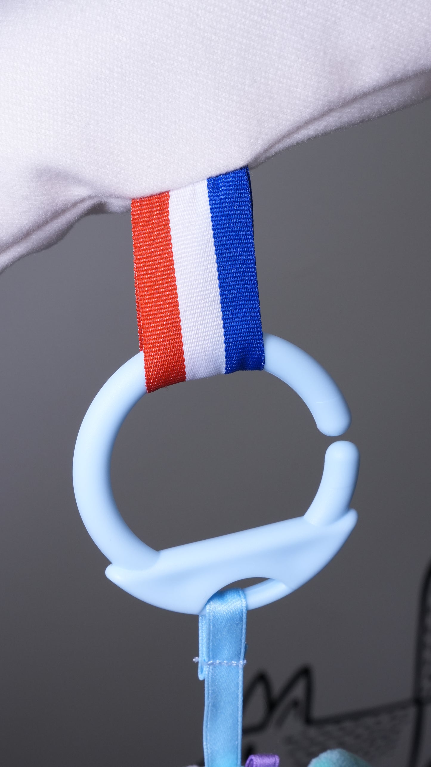 Close-up of a colorful ring attached to a play gym, featuring red, white, and blue stripes for easy grip.